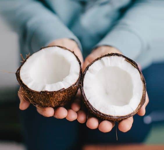 Person holding a halved coconut.