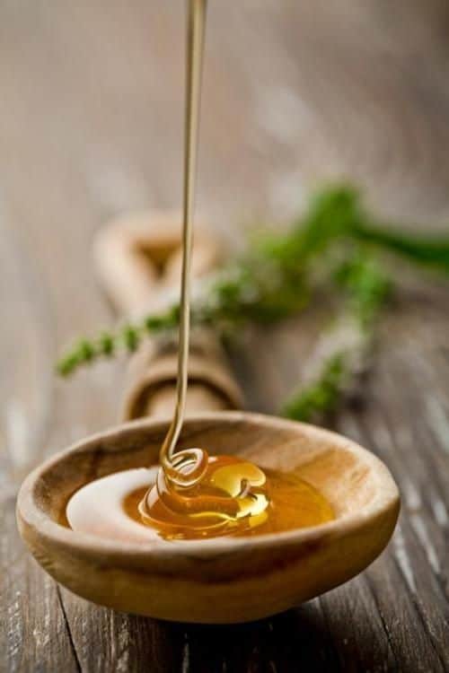 Honey drizzling into a wooden bowl.