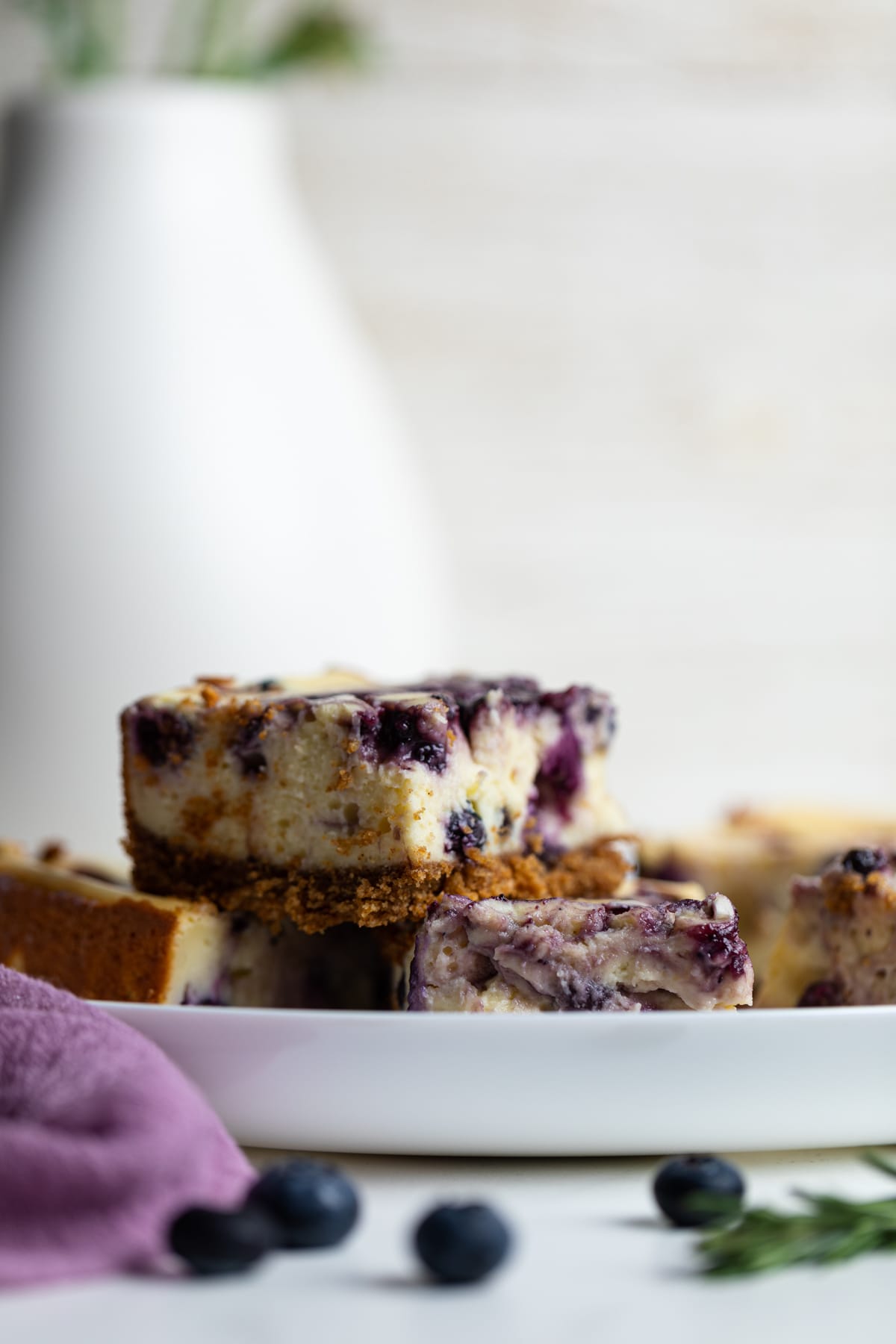 Lemon Blueberry Cheesecake Bars in a stack on a white plate.