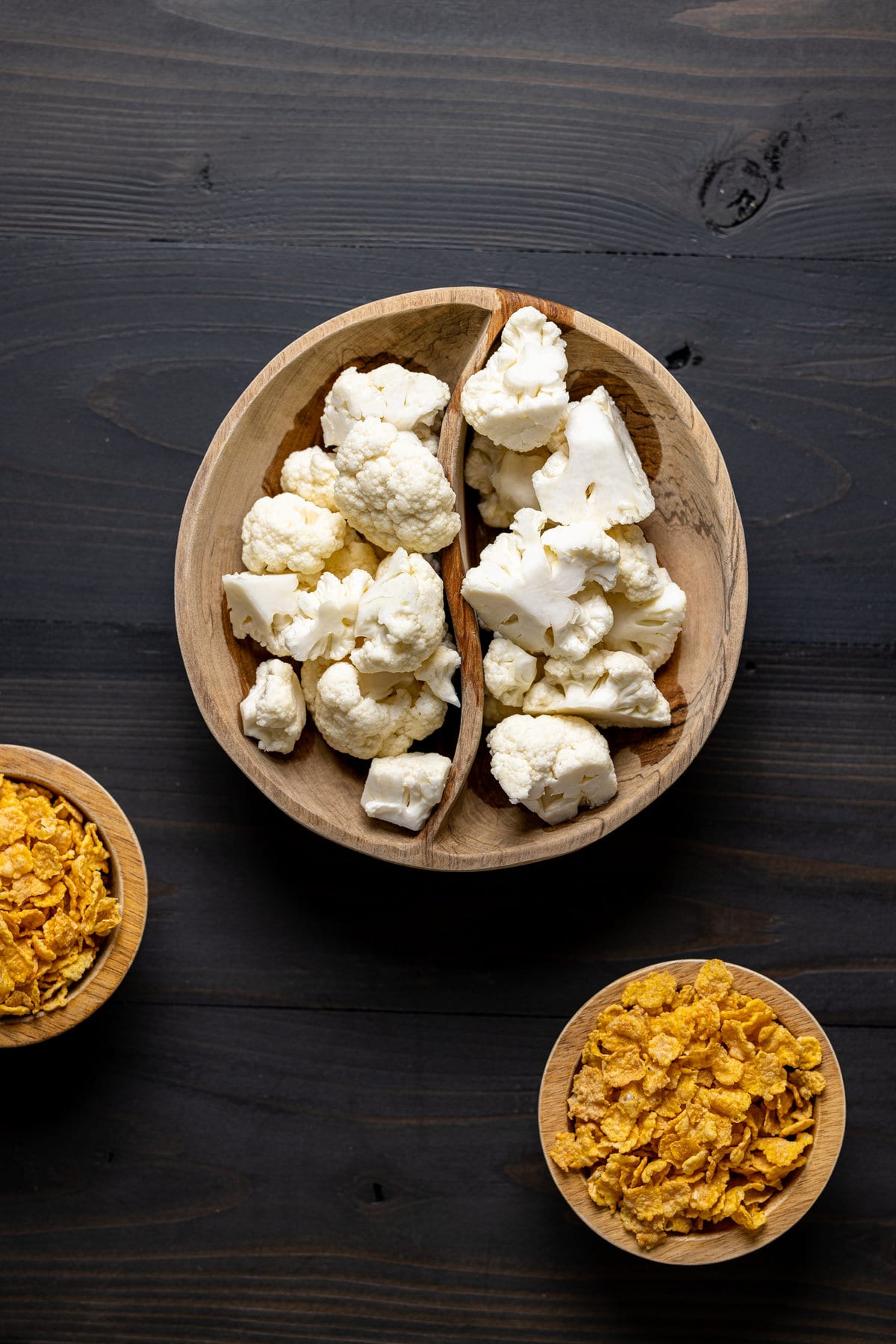 Wooden bowls of chopped cauliflower and corn flakes