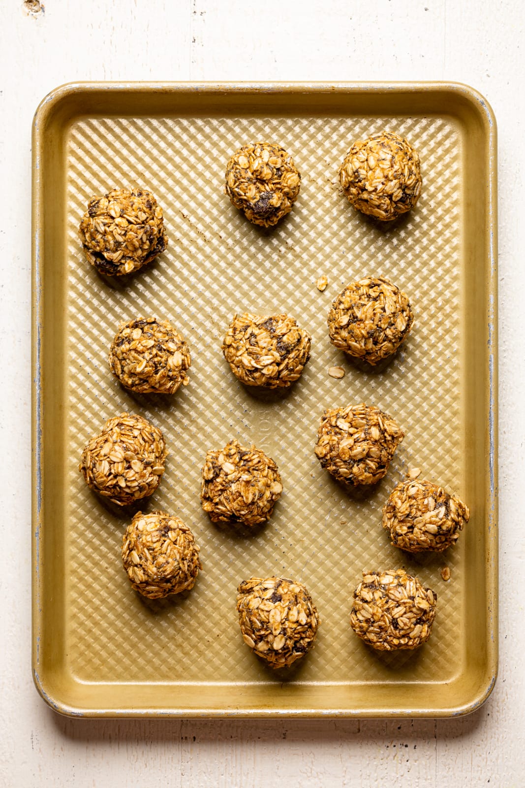 Protein balls on a gold baking sheet lined side by side.