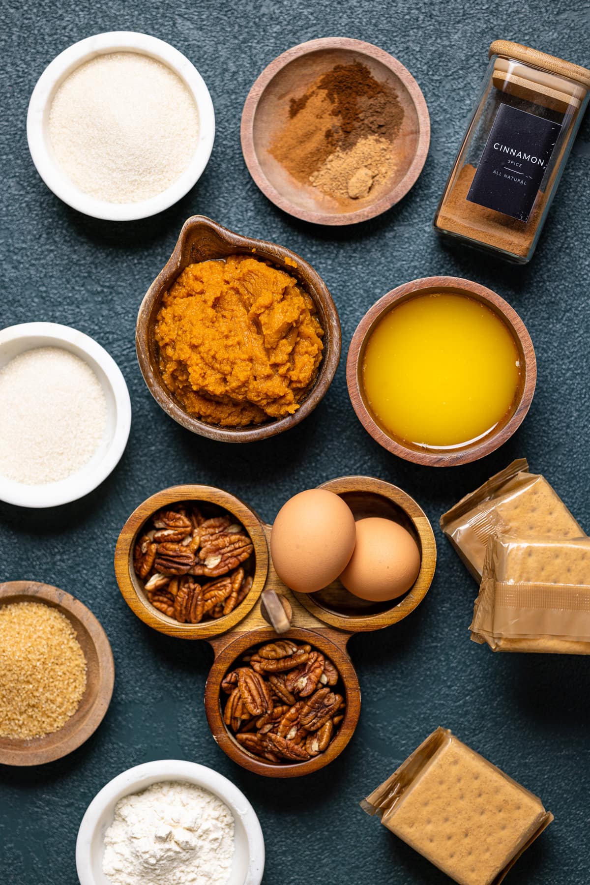 Ingredients for Caramel Pumpkin Cheesecake with a Pecan Crust including eggs, graham crackers, and cinnamon