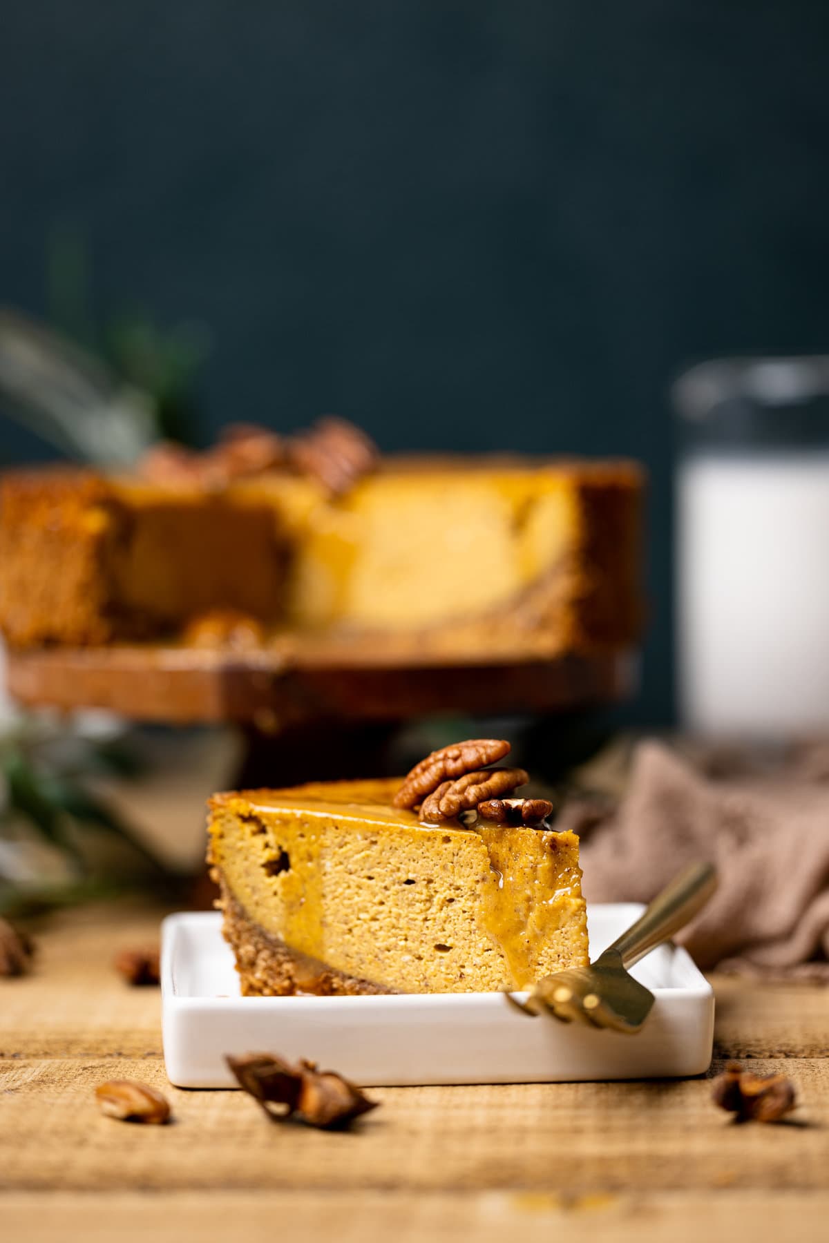 Slice of Caramel Pumpkin Cheesecake with a Pecan Crust next to a fork