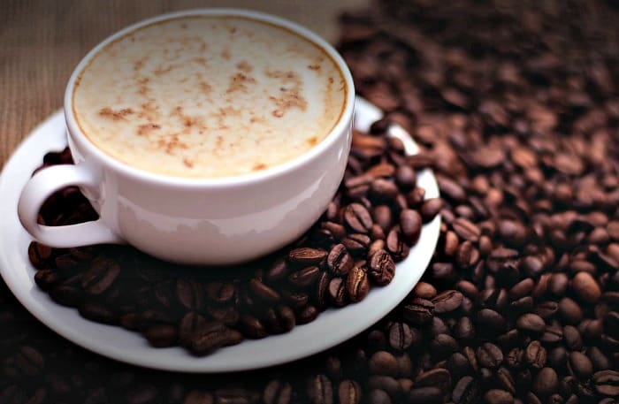 Cup of coffee surrounded by coffee beans.