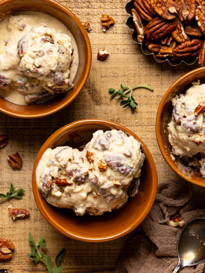 Up close shot of three bowls of ice cream with pecans and herbs.