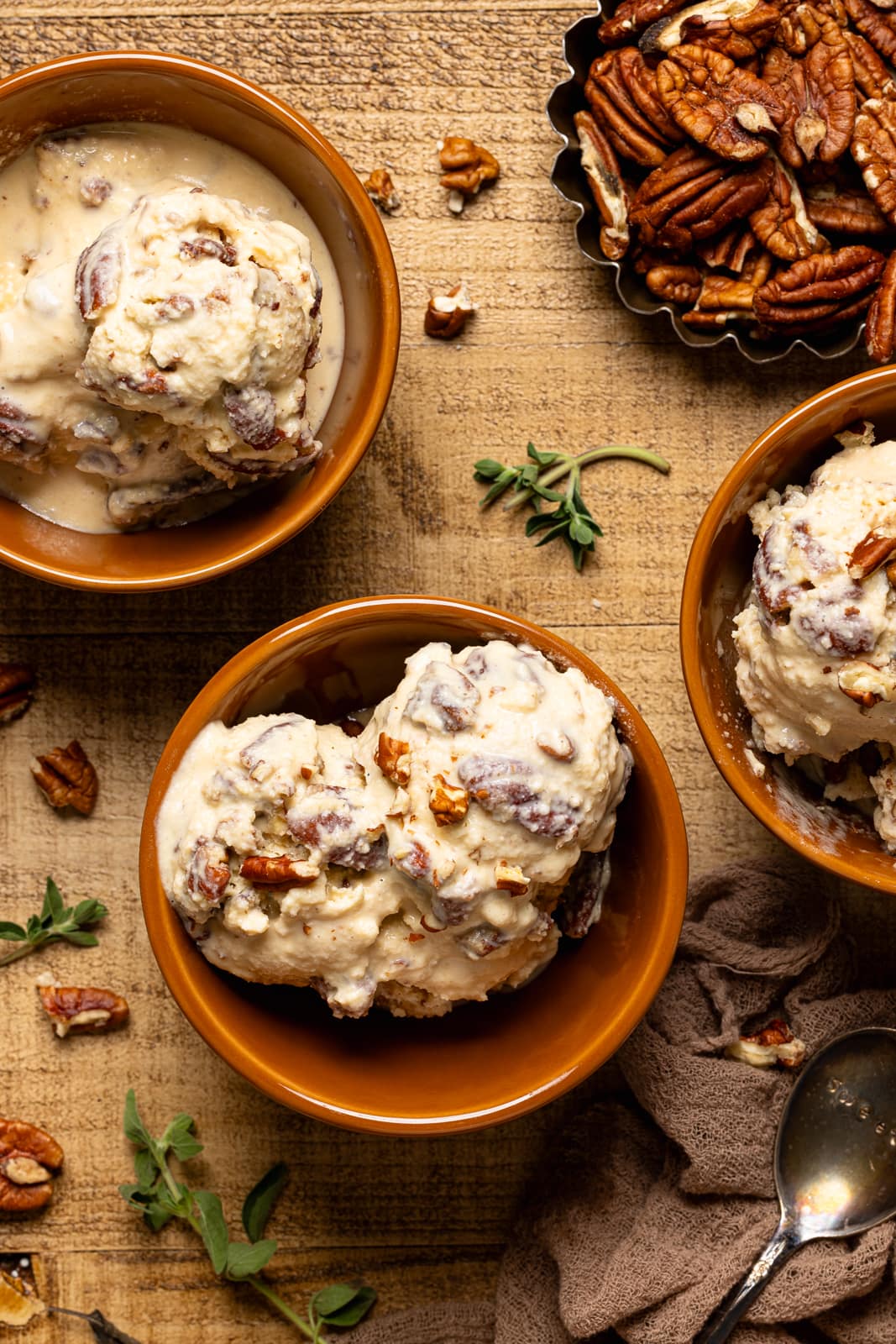 Up close shot of three bowls of ice cream with pecans and herbs.