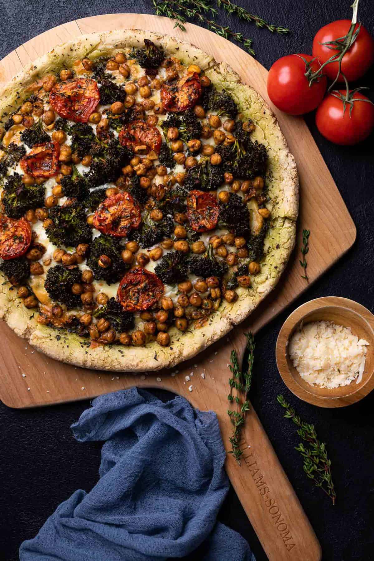 Whole Chickpea and Veggie Gluten-Free Pesto Pizza on a wooden board.