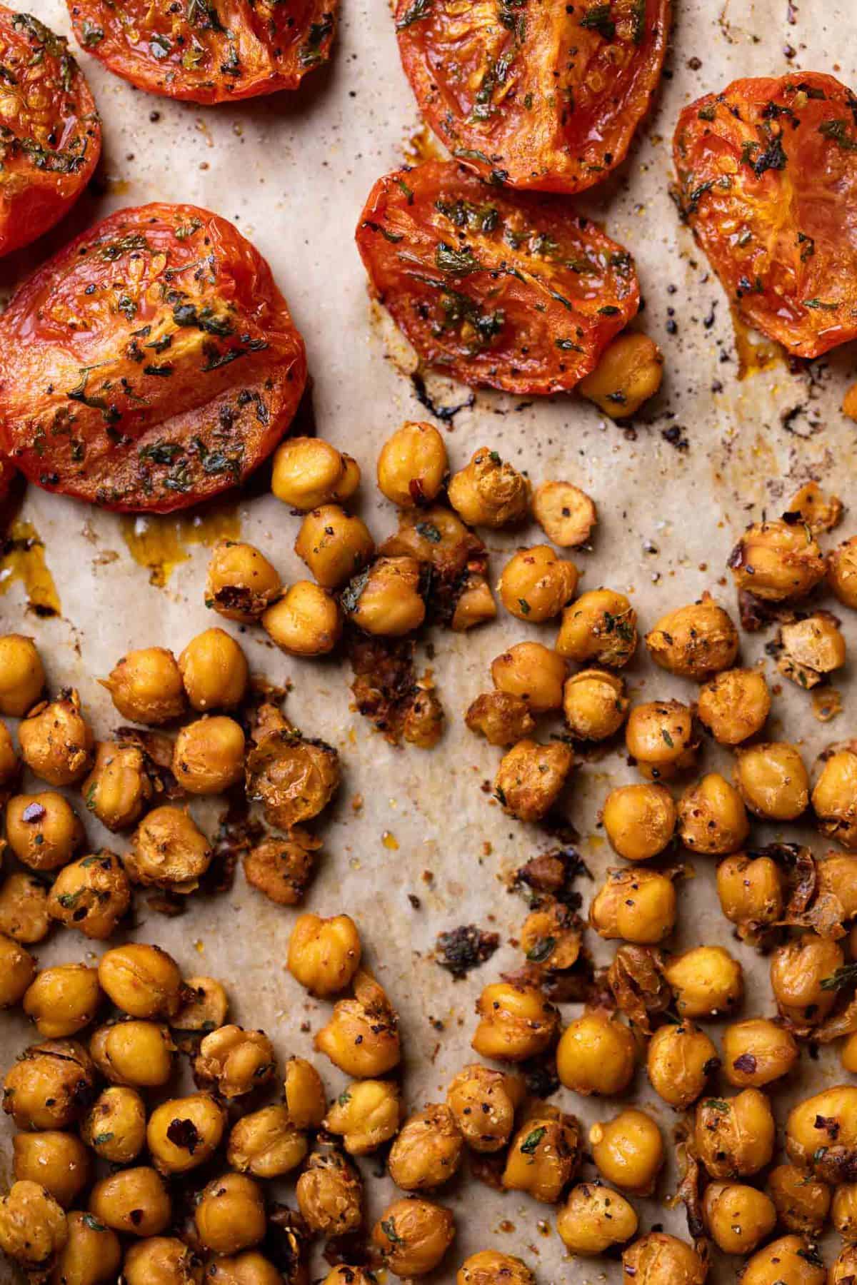 Roasted chickpeas and tomatoes on parchment paper.