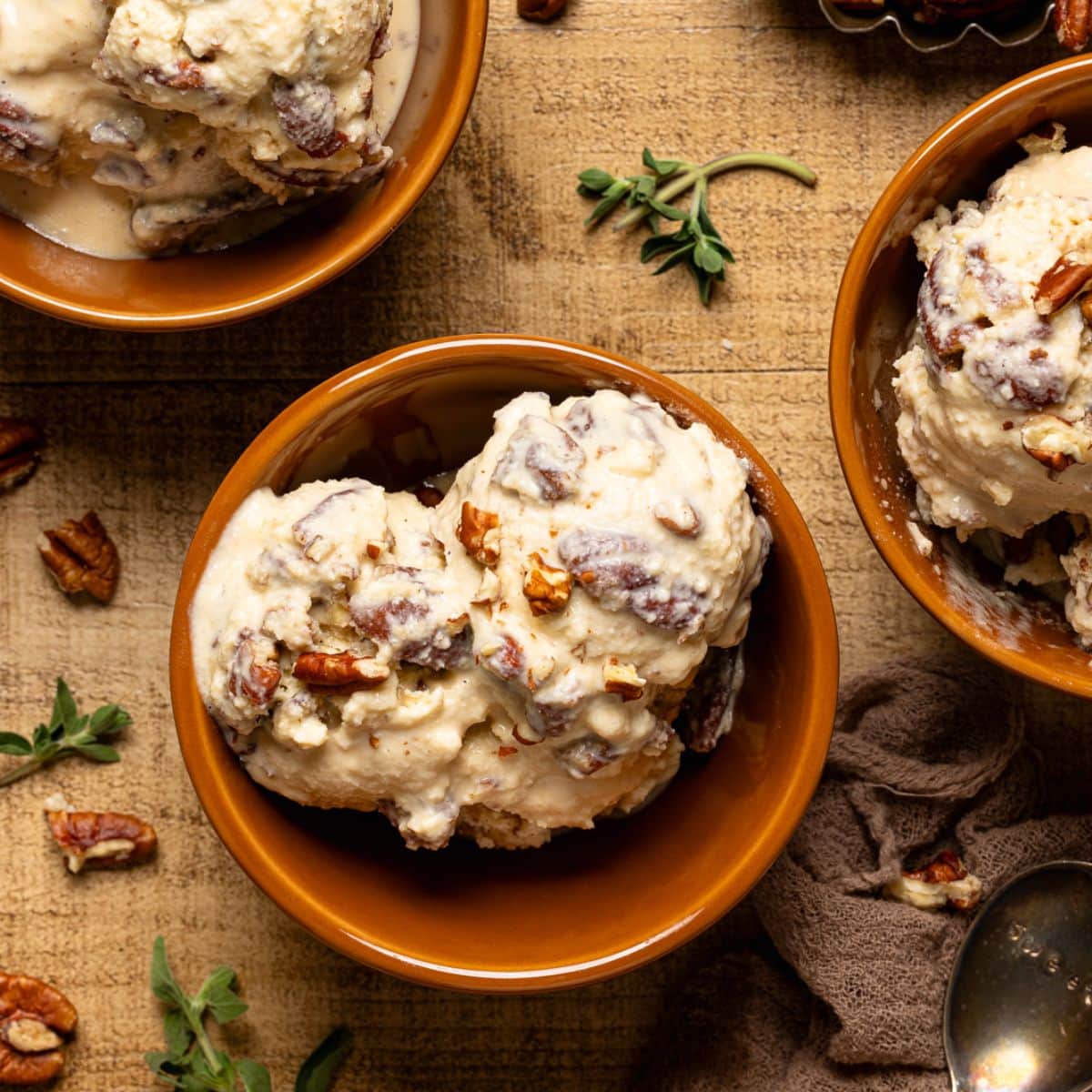 Up close shot of three bowls of ice cream with pecans and herbs.