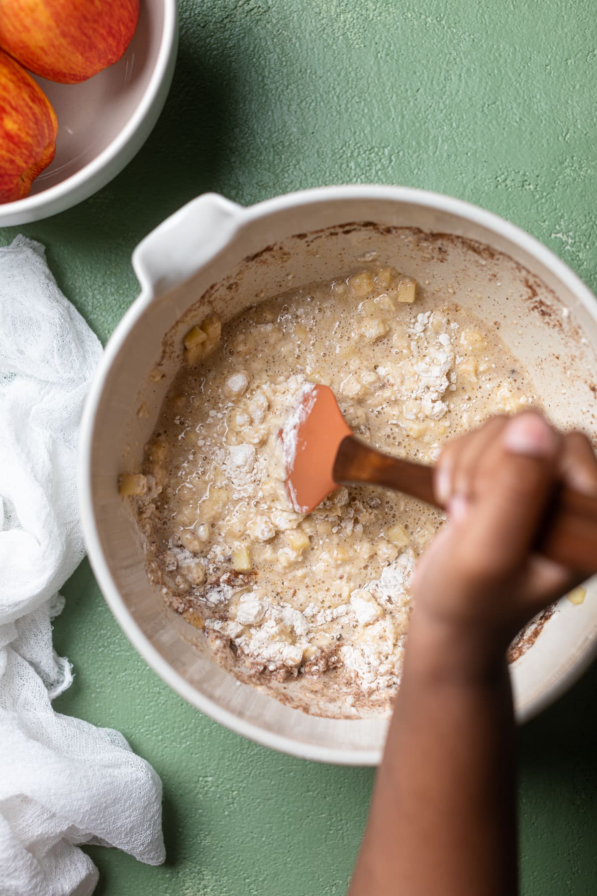 Hand using a spatula to stir Vegan Apple Cinnamon Pancake batter