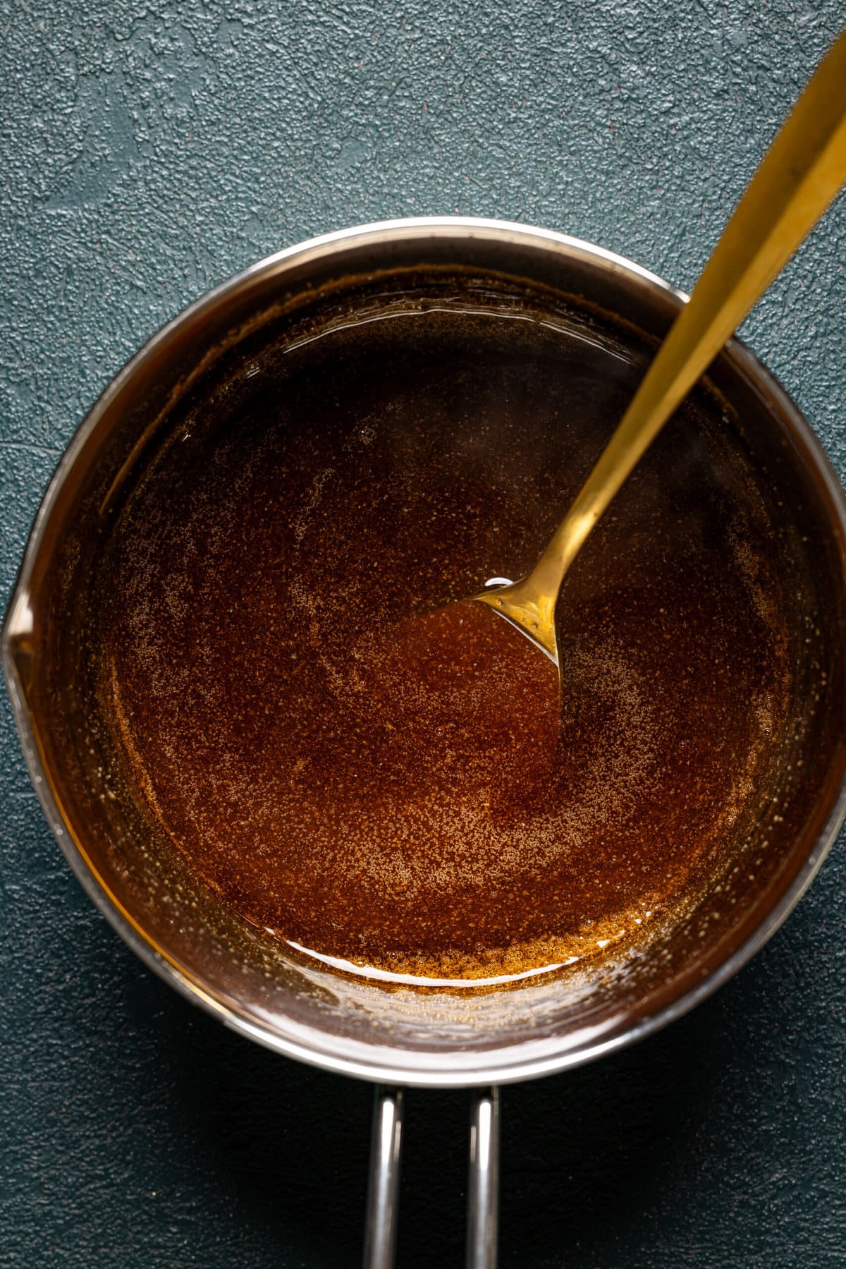 Teriyaki sauce in a saucepan with a spoon.