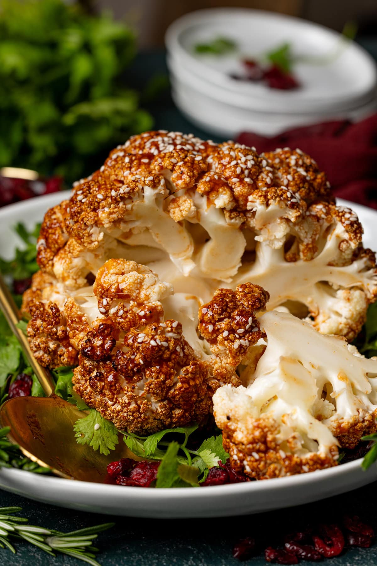 Cauliflower slices on a serving platter with spoon and garnish. 