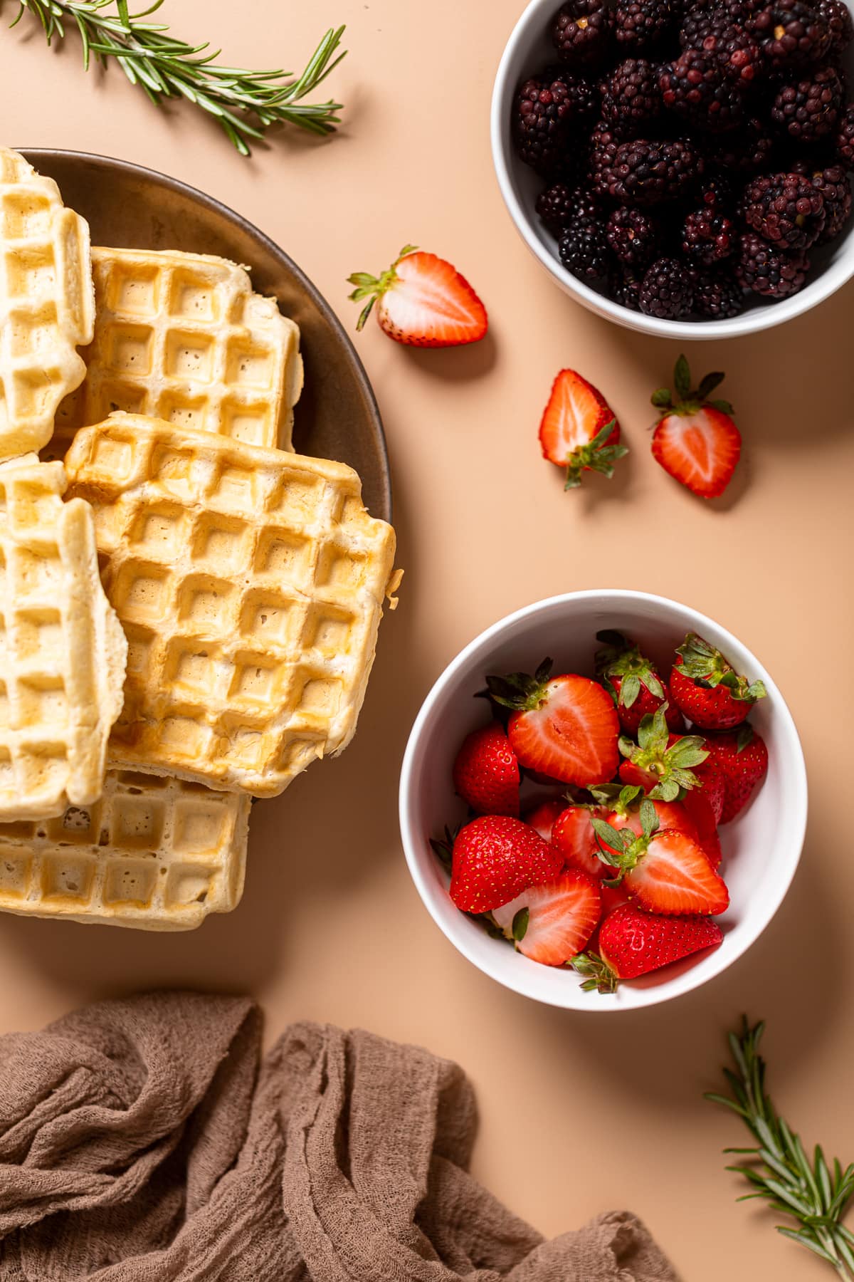 Fluffy Cinnamon Vegan Belgian Waffles next to bowl of strawberries and blackberries.