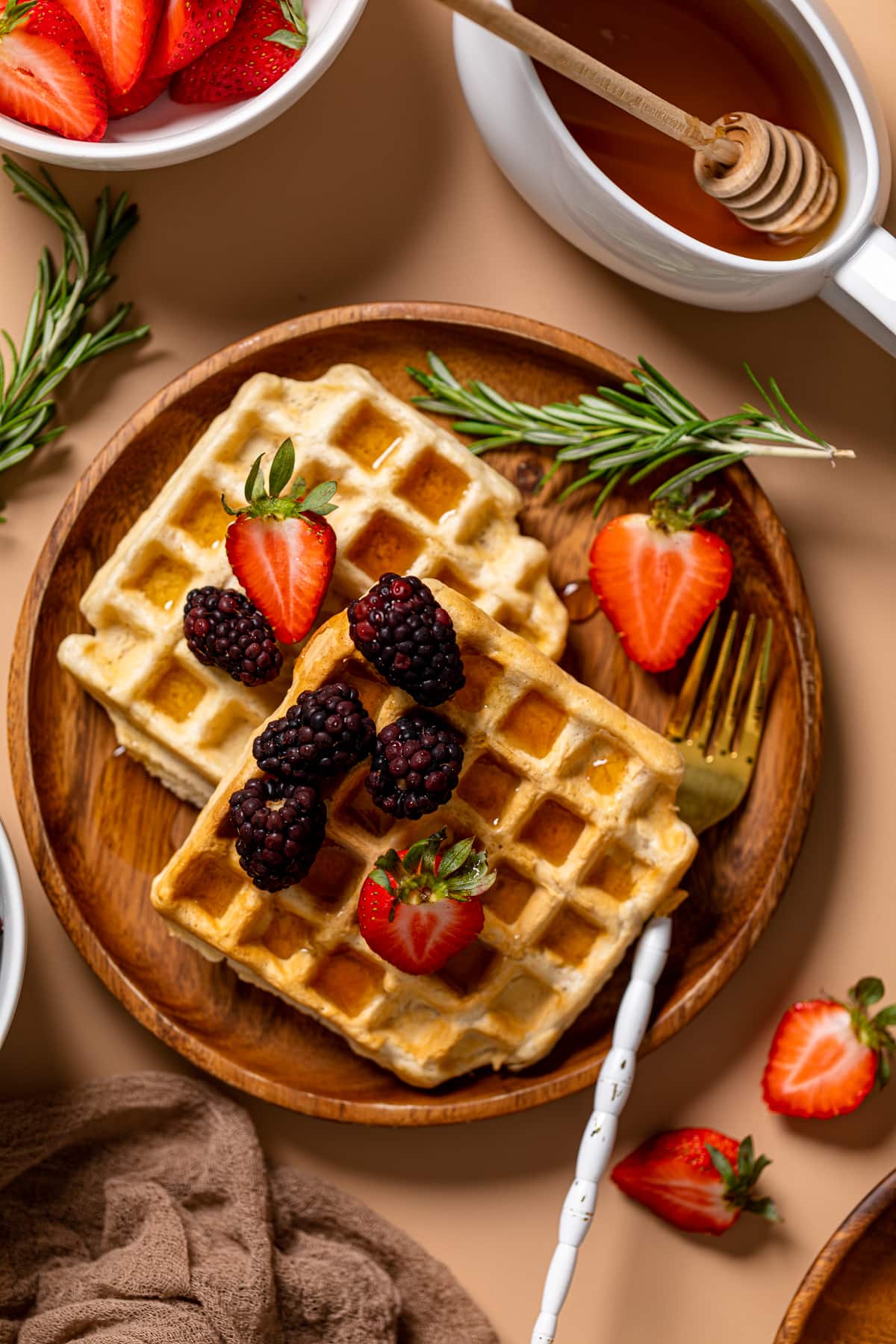 Wooden plate with Fluffy Cinnamon Vegan Belgian Waffles, fruit, and a fork.