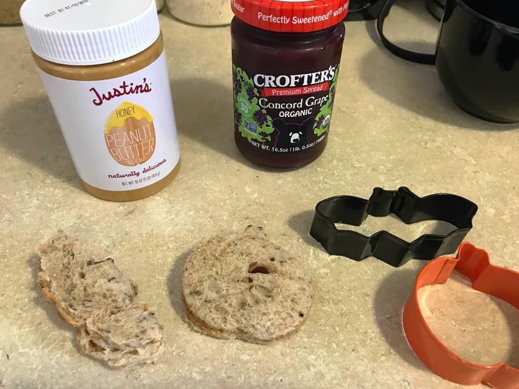 Sandwiches cut into shapes in front of jars of peanut butter and jelly.