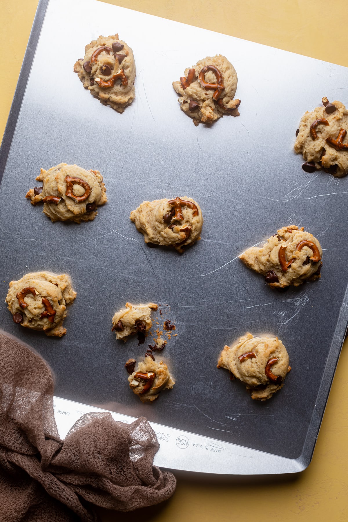 Scoops of Vegan Chocolate Chip and Pretzel Cookie dough on a baking sheet.