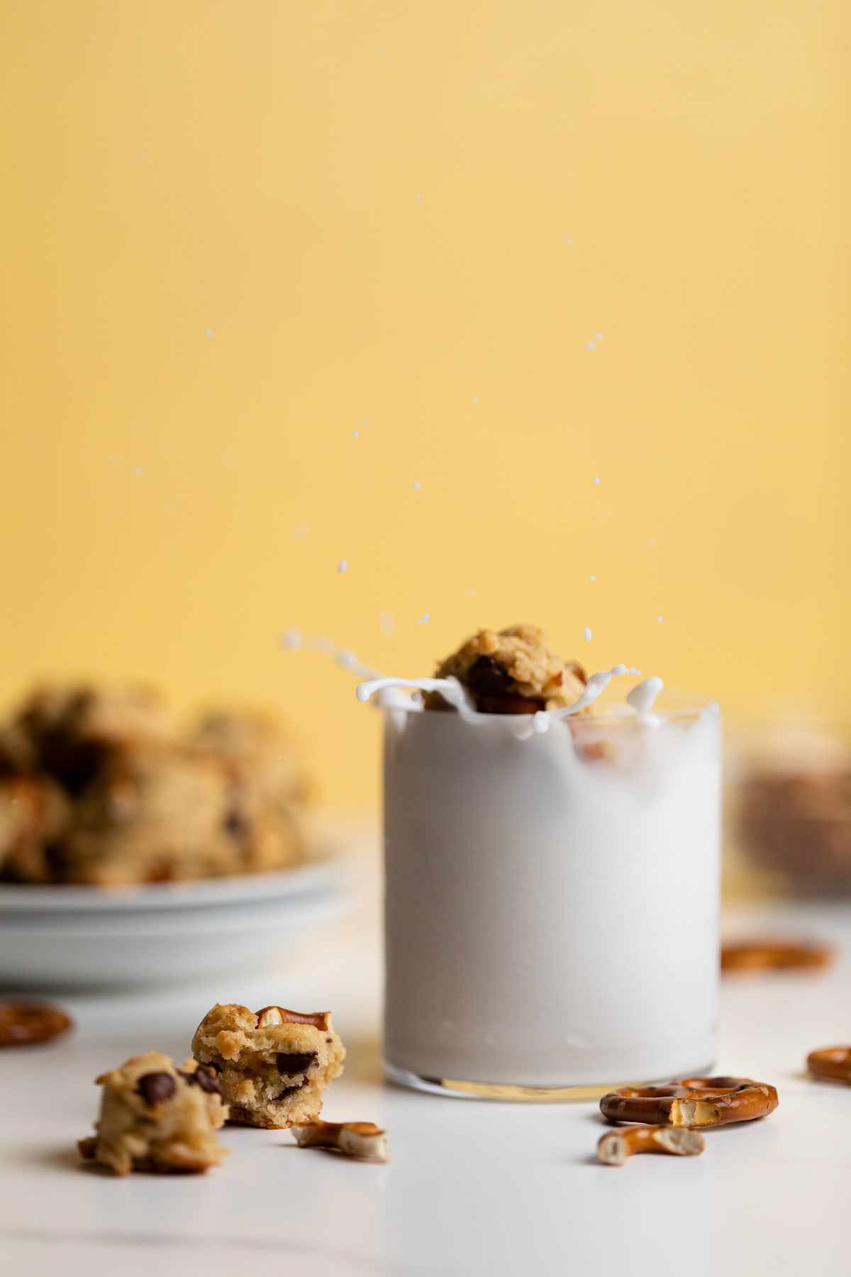 Chunky Vegan Chocolate Chip and Pretzel Cookie dunking into a glass of milk.