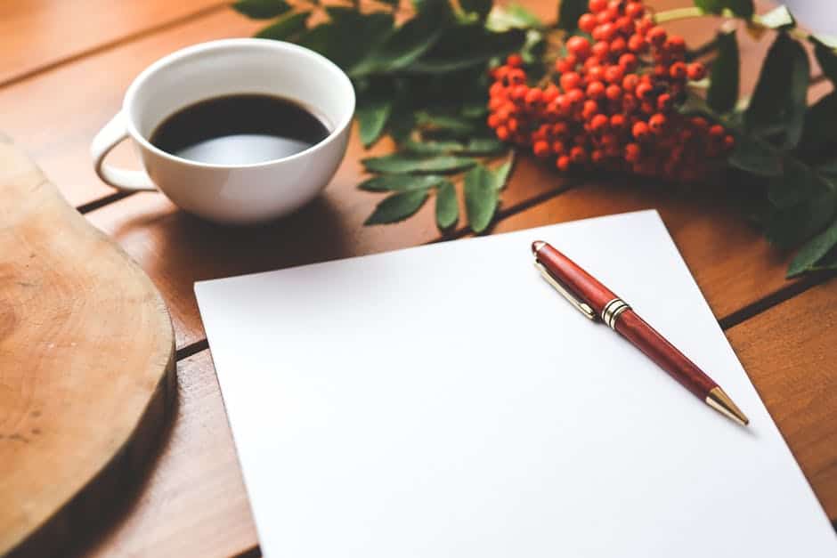 Blank piece of paper with a pen next to a coffee mug.