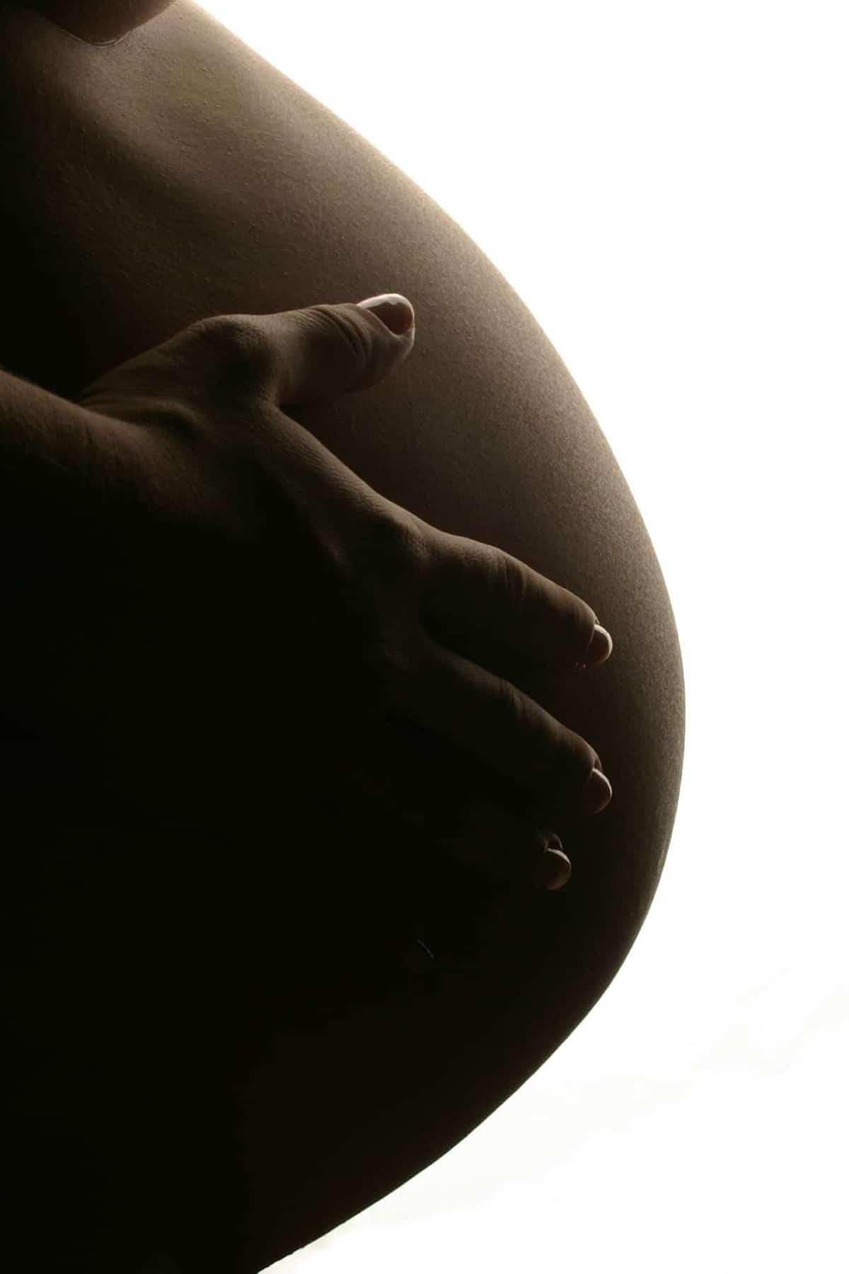 Woman with her hands on her pregnant belly.
