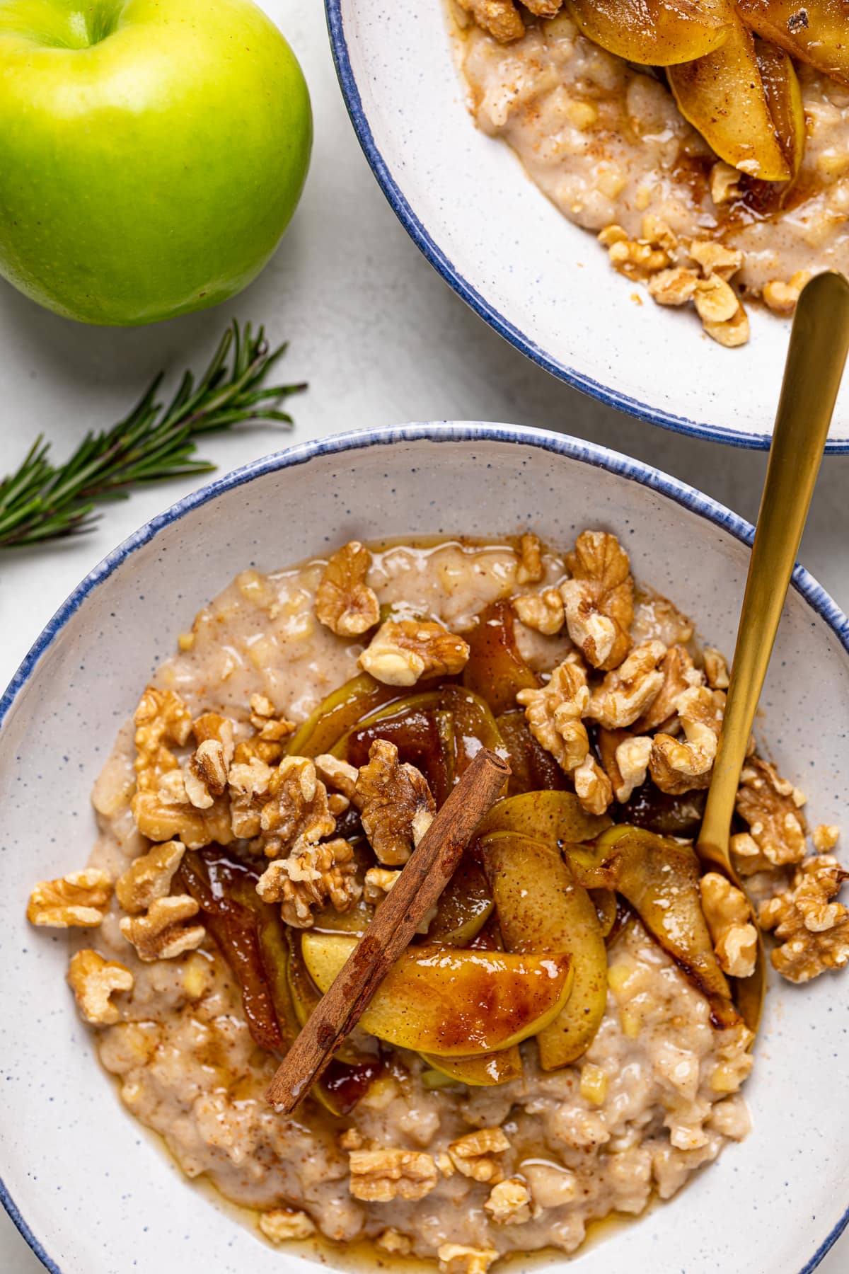 Bowl of Apple Cinnamon Oatmeal Porridge topped with cinnamon sticks, nuts, and caramelized apples