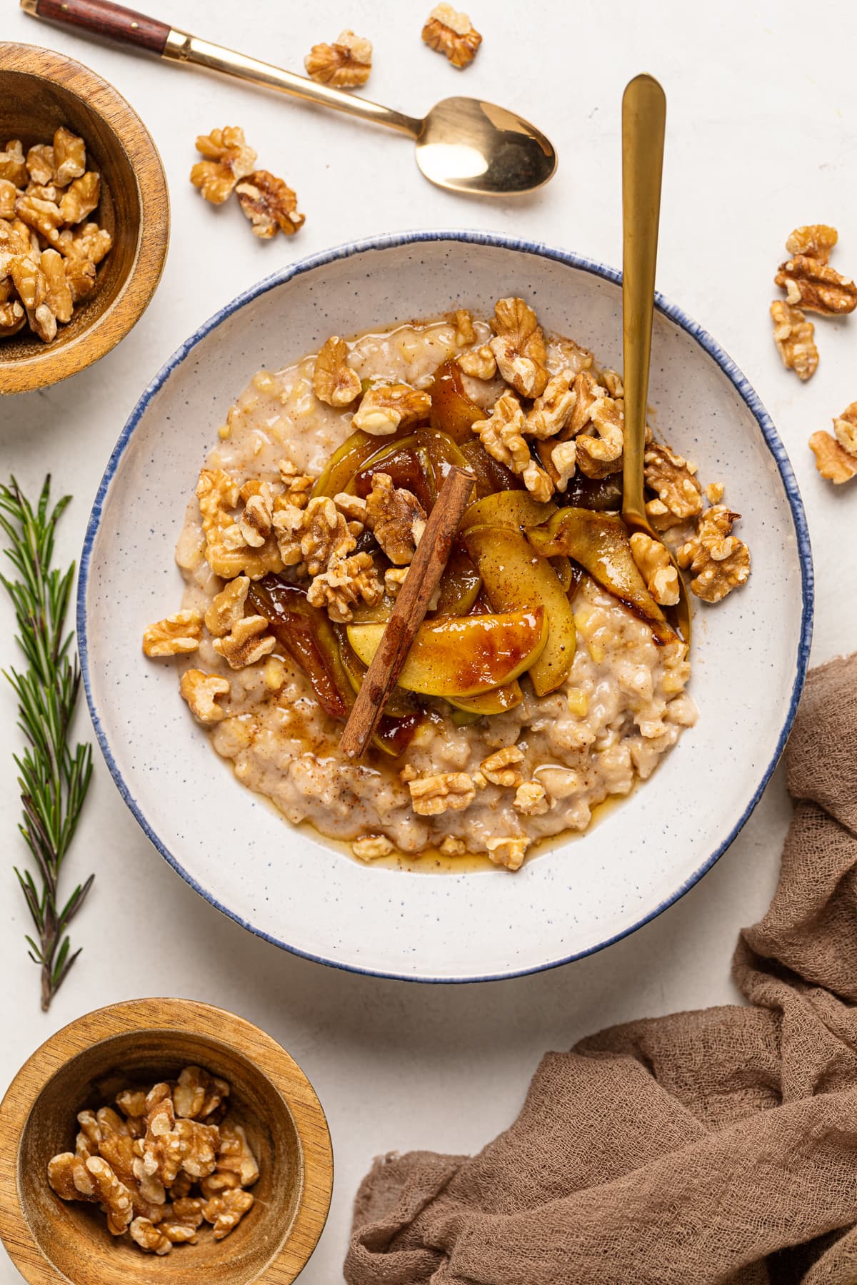 Bowl of Apple Cinnamon Oatmeal Porridge topped with cinnamon sticks, nuts, and caramelized apples