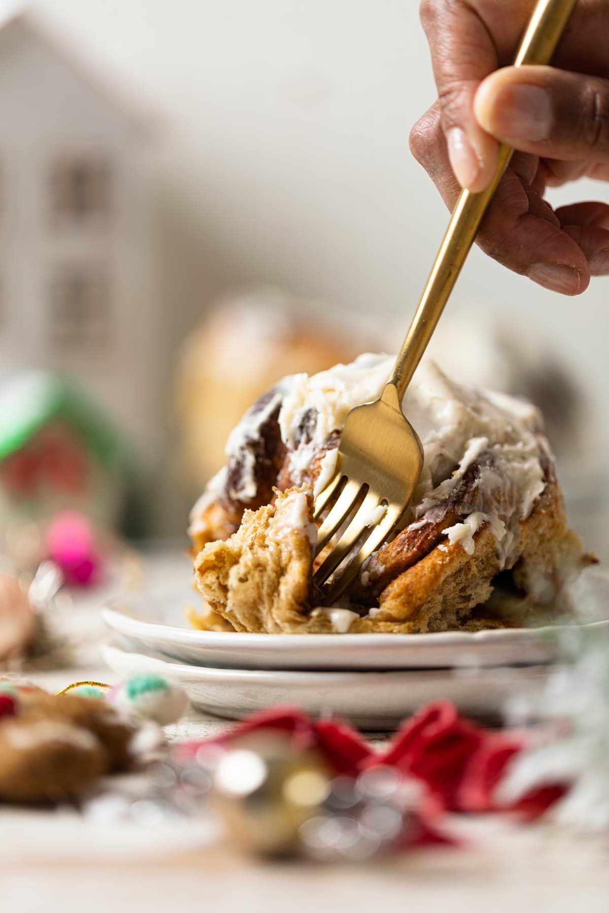 Fork digging into a Gingerbread Cinnamon Roll with Maple Cream Cheese Frosting 