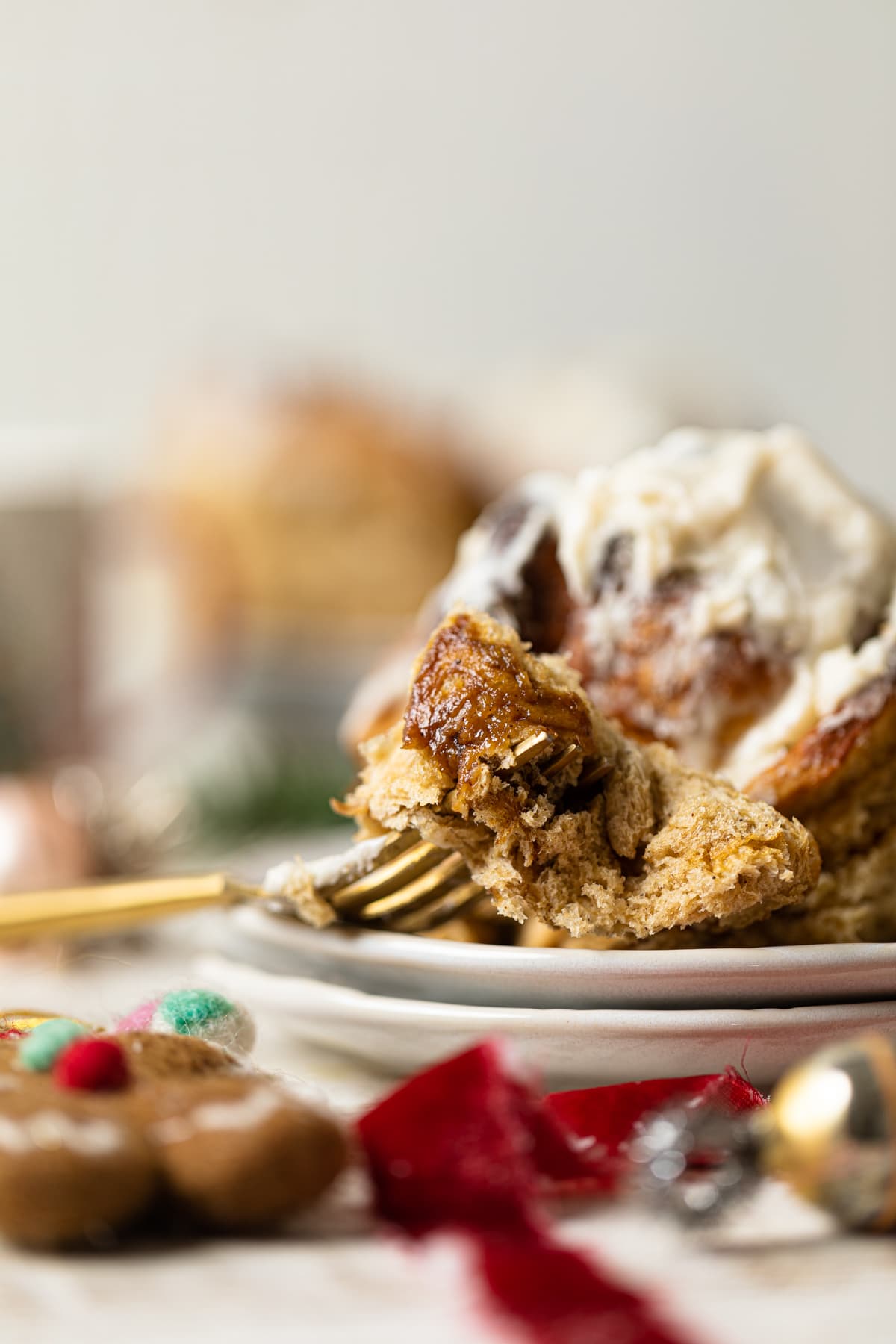 Fork with a piece of a Gingerbread Cinnamon Roll with Maple Cream Cheese Frosting 