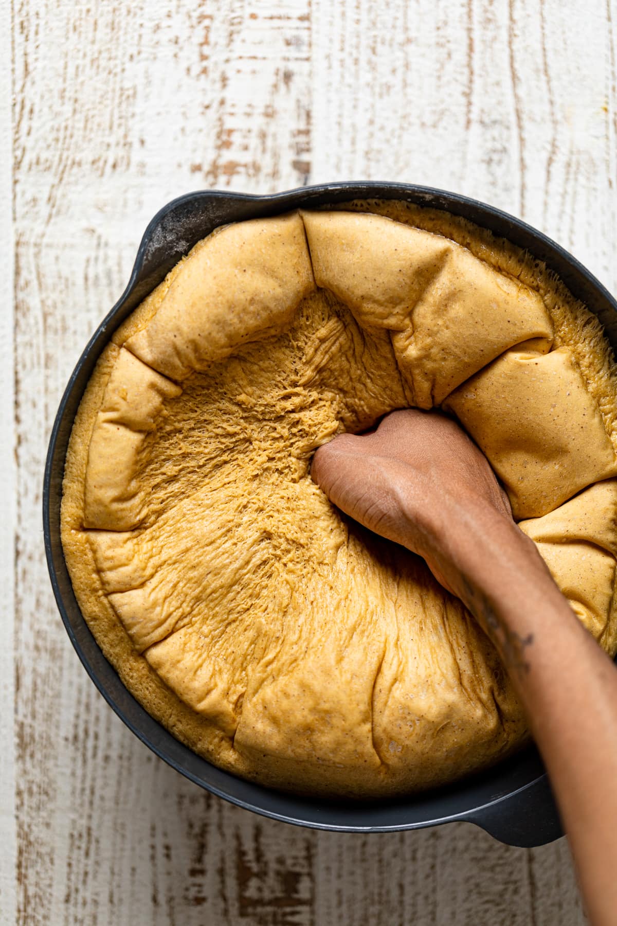 Hand punching down risen Gingerbread Cinnamon Roll dough