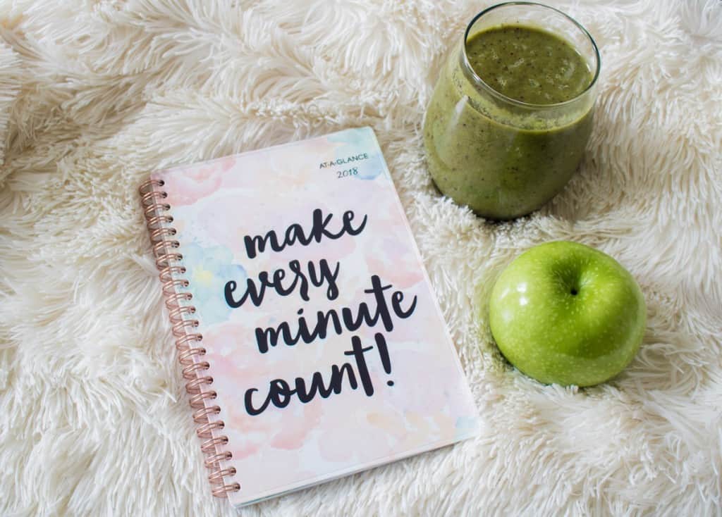 Green smoothie next to a notebook that reads \"make every minute count!\"