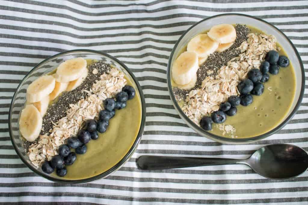 Two smoothie bowls topped with bananas, blueberries, chia seeds, and oats.