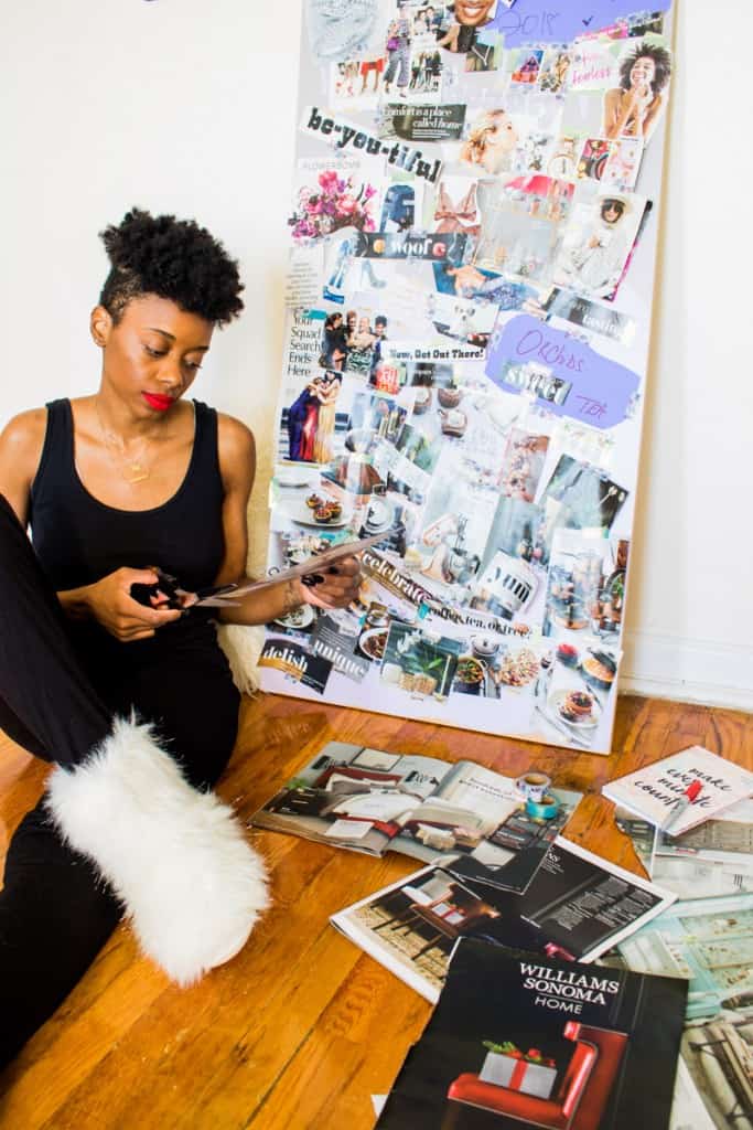 Shanika sitting in front of a vision board while cutting things out of a magazine.