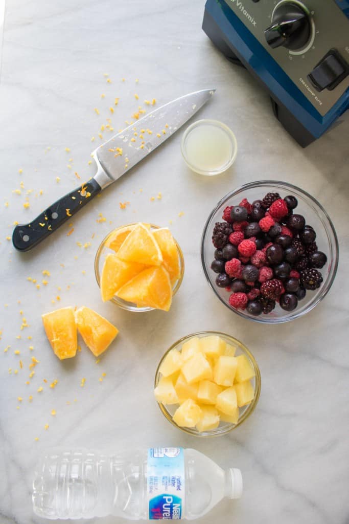 Bowls of fruit on a counter with a knife.