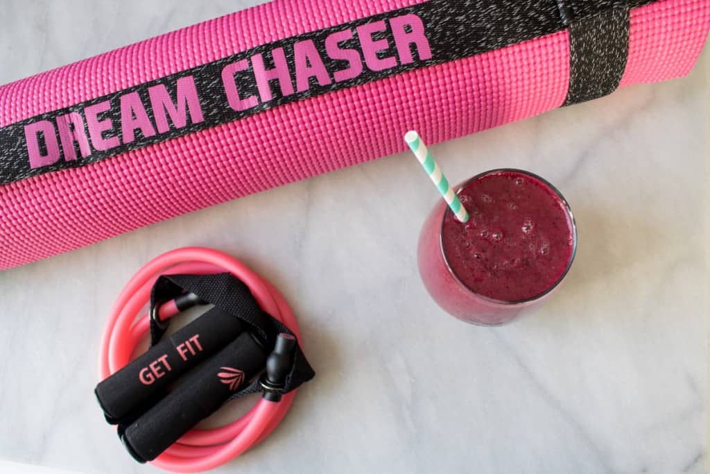 Red smoothie next to exercise equipment.