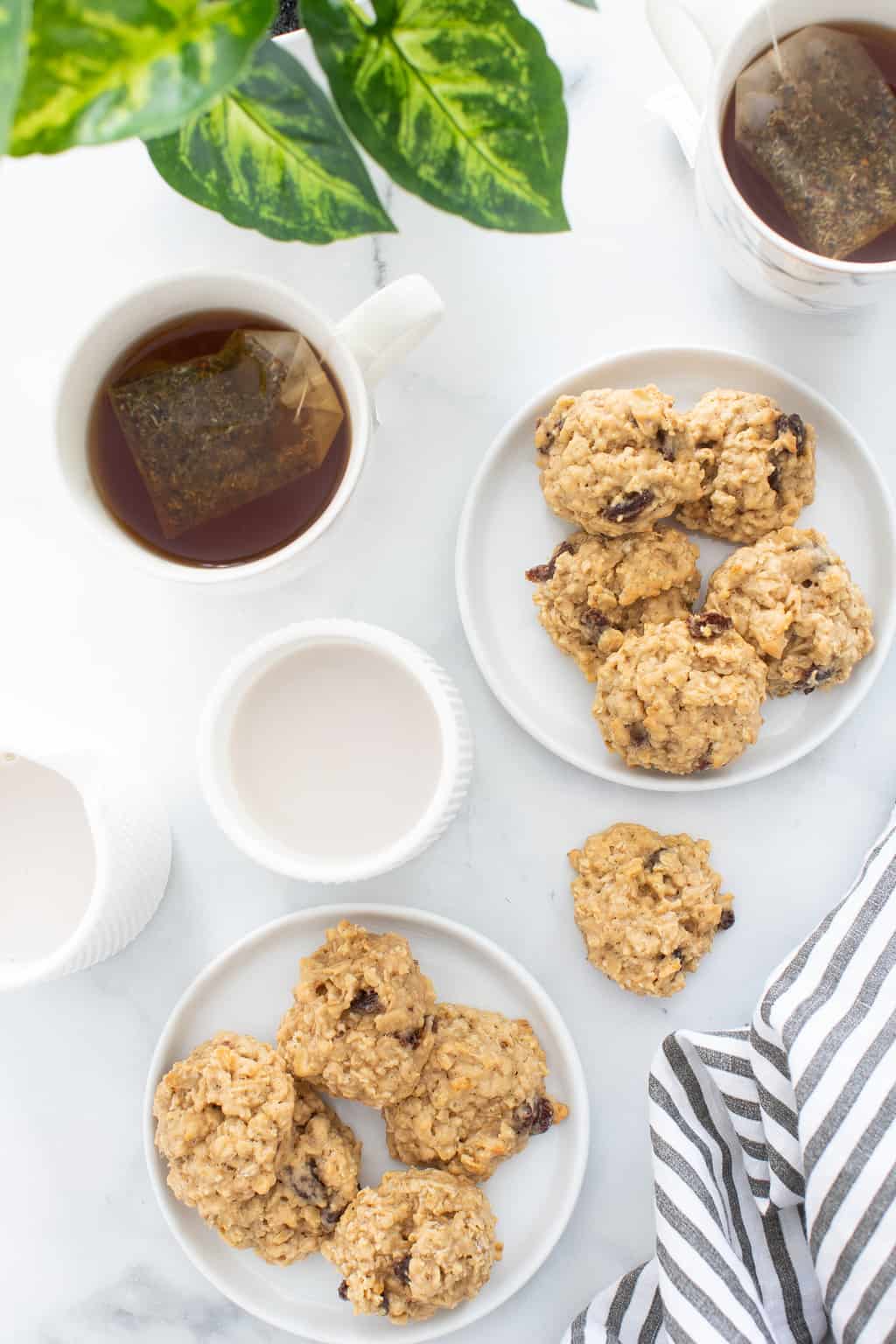 Two plates of Chewy Apple Oatmeal Raisin Breakfast Cookies with a mug of tea.