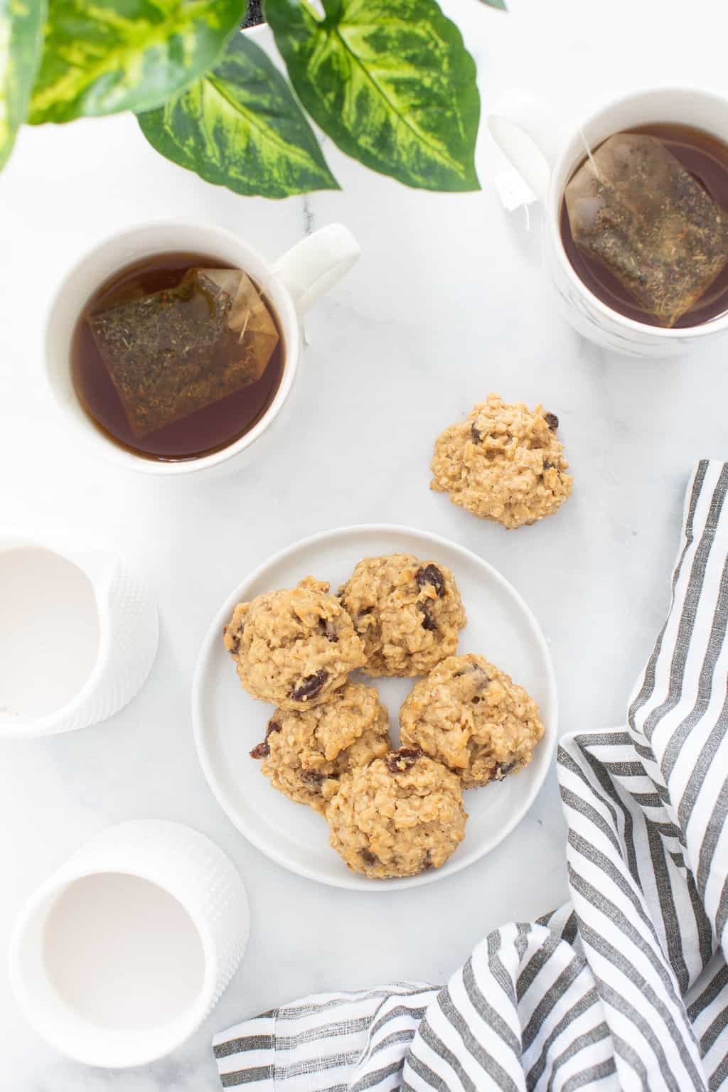 Plate of Chewy Apple Oatmeal Raisin Breakfast Cookies with two mugs of tea.