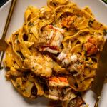 Closeup of Creamy Tuscan Lobster Pasta with a fork and a knife