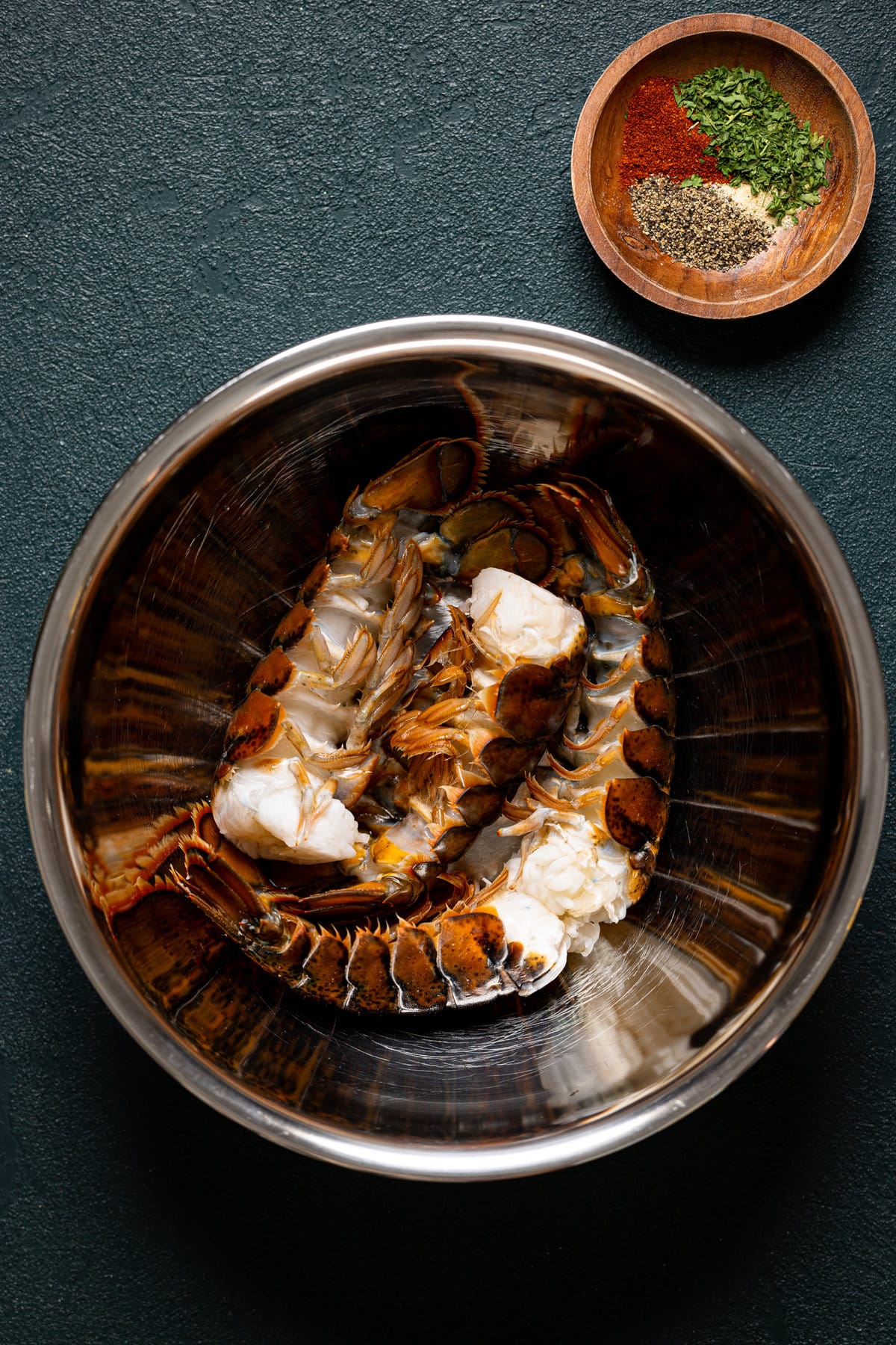 Bowl of lobster tails next to a bowl of seasonings