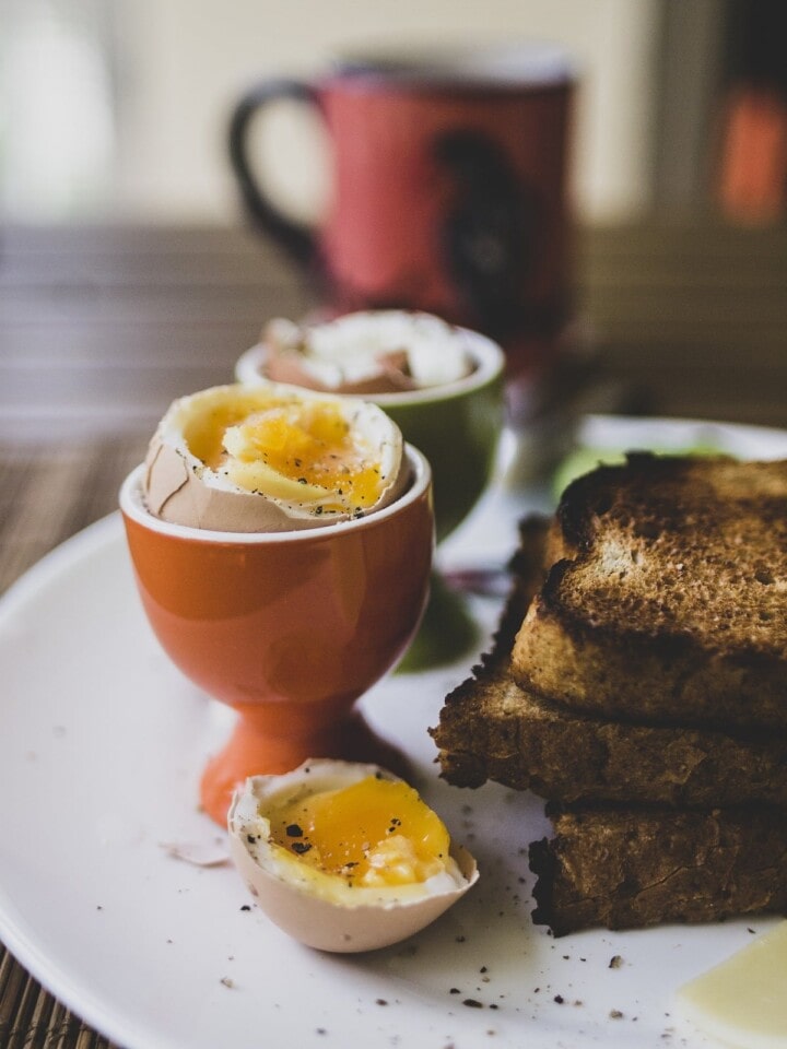 Broken softboiled egg near a stack of toast