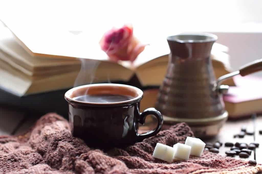 Steaming mug on a knit fabric with sugar cubes.