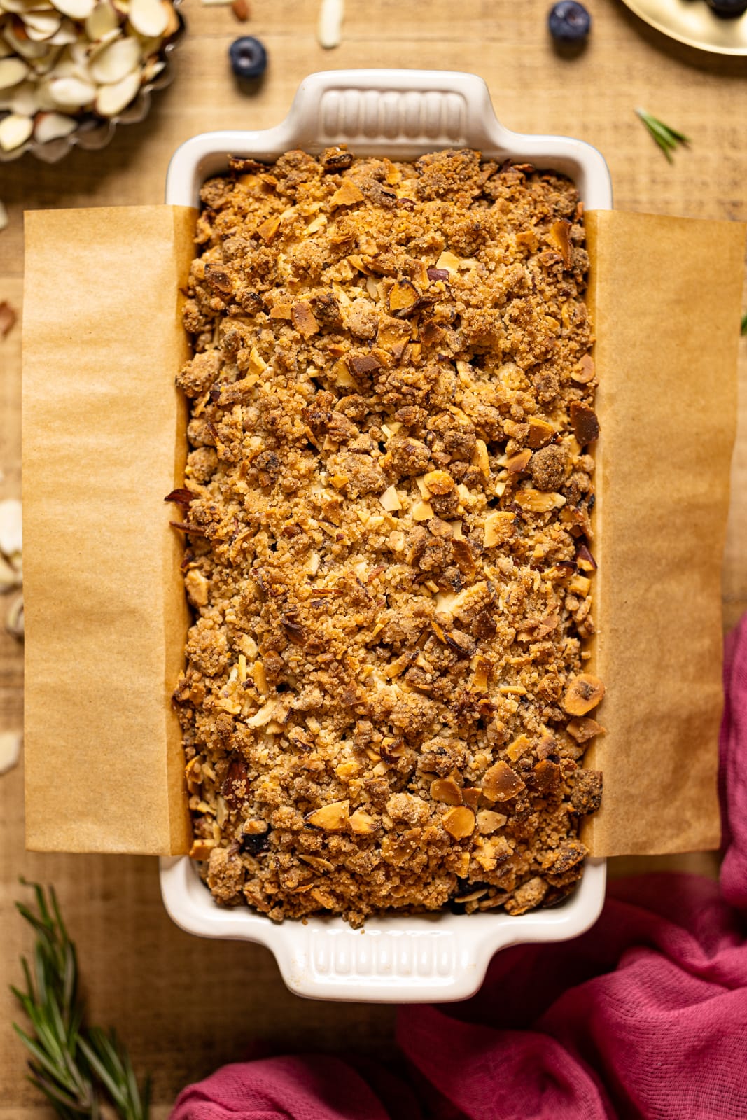 Up close bread in a loaf pan on a brown wood table with parchment paper.