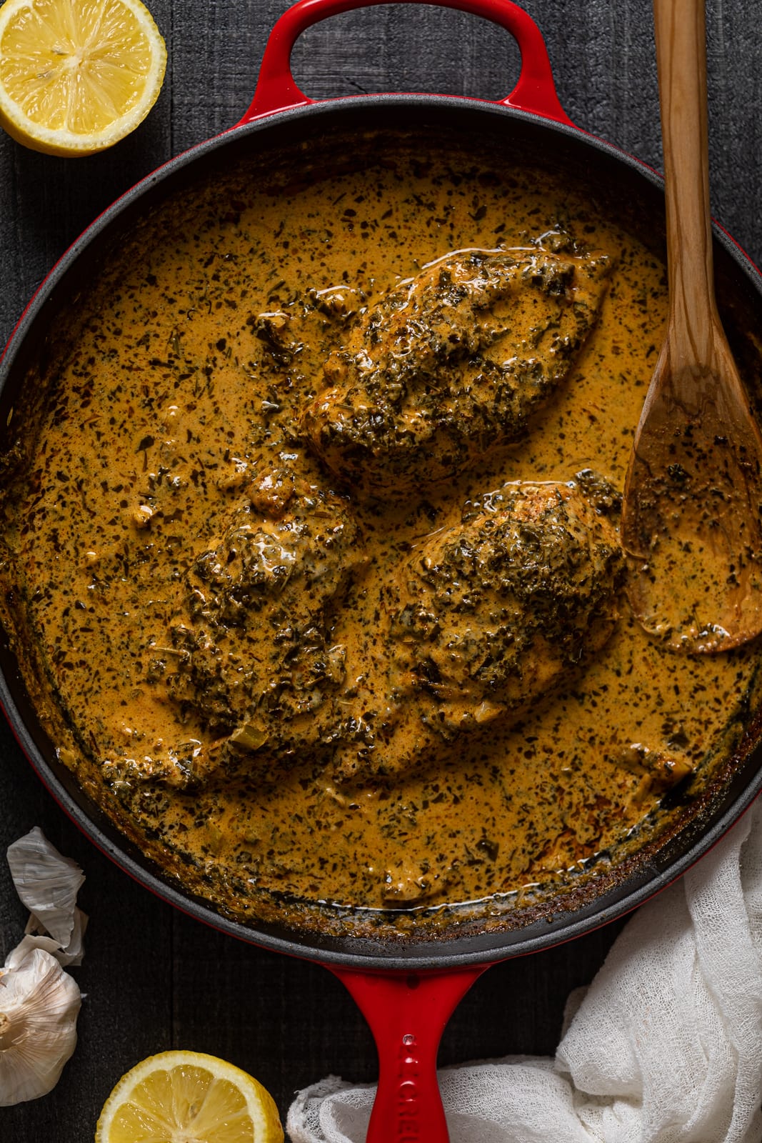 Wooden spoon in a skillet of Creamy Lemon and Herb Parmesan Chicken