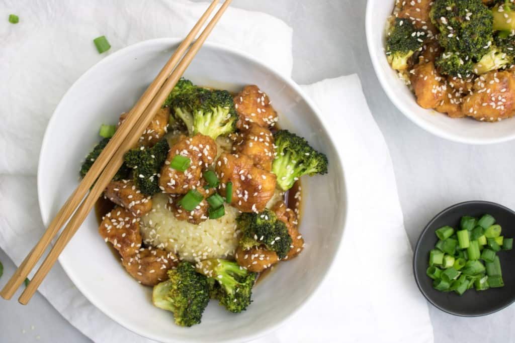 Chopsticks on a bowl of broccoli and chicken.