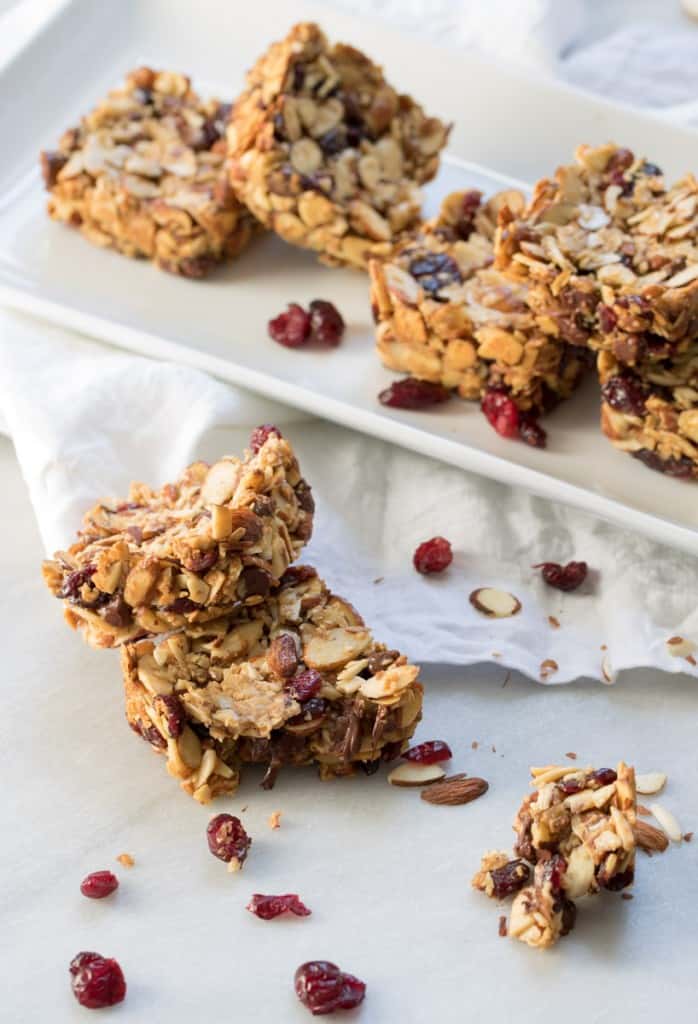 Chocolate Cranberry Almond Snack Bars stacked in front of a plate.