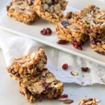 Chocolate Cranberry Almond Snack Bars stacked in front of a plate.
