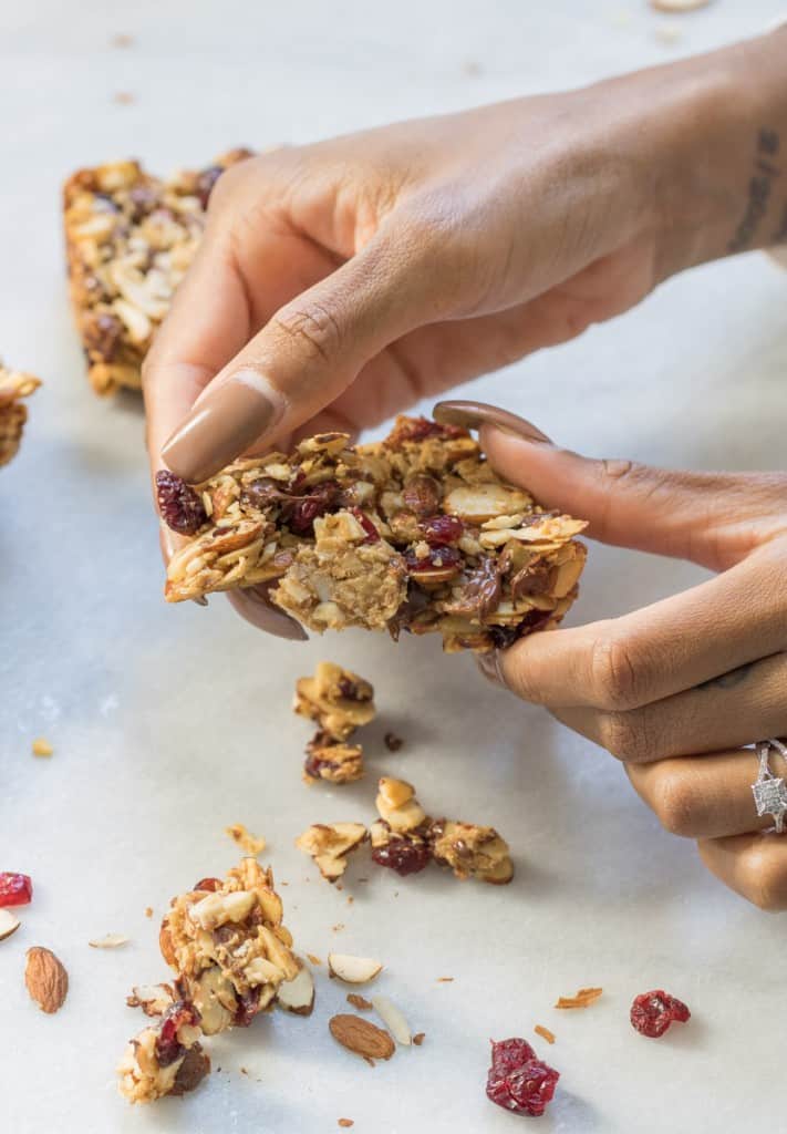 Woman pulling apart a Chocolate Cranberry Almond Snack Bar.