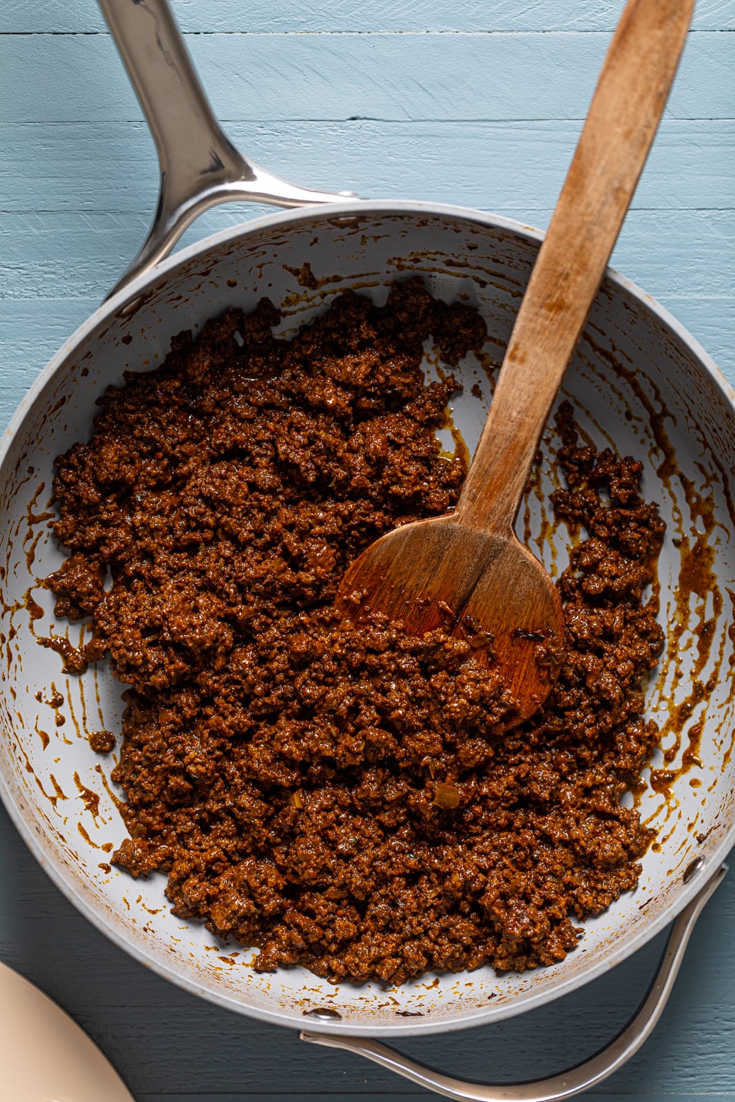 Wooden spoon stirring a pan of Spicy Jamaican Beef Patty filling