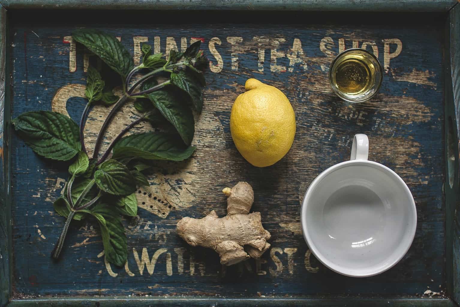 Lemon, ginger, water, and other ingredients on a tray.