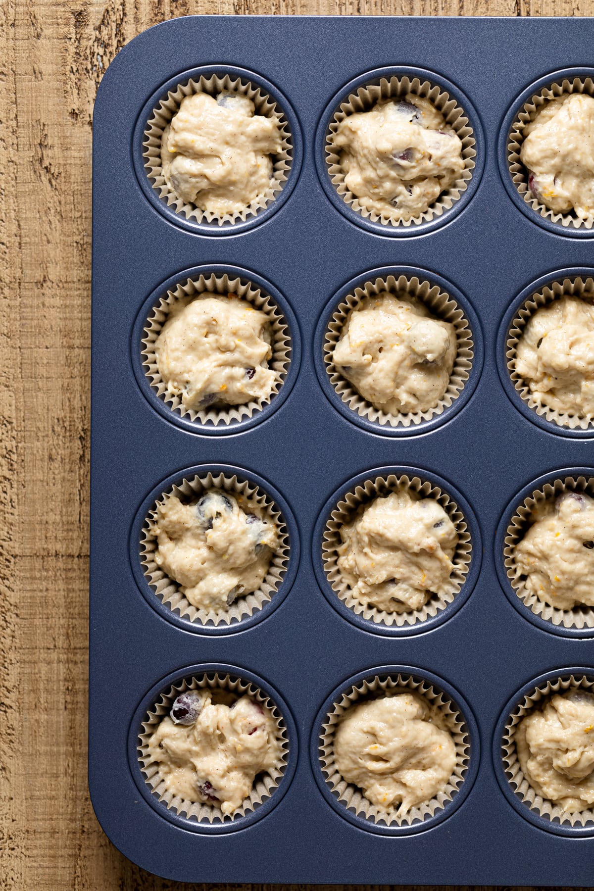Muffin pan filled with liners and Vegan Orange Cranberry Breakfast Muffin batter