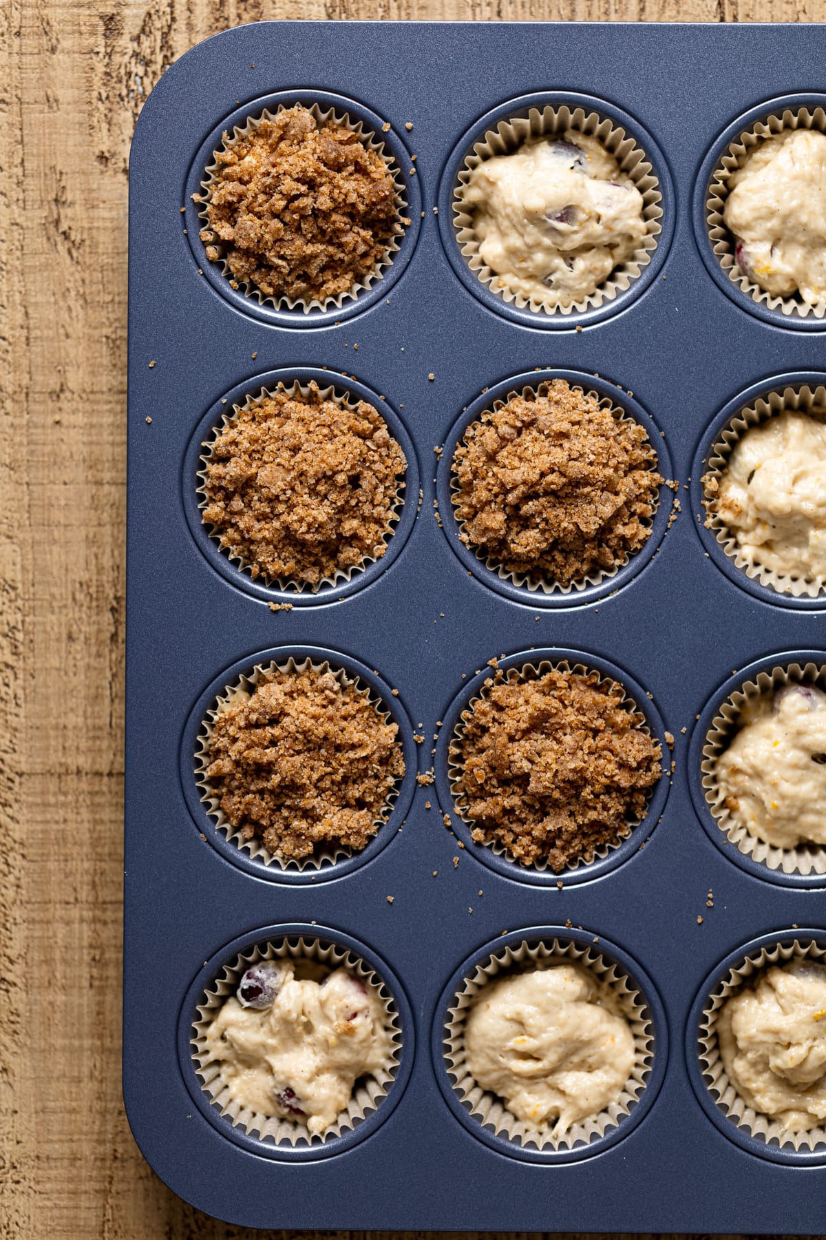 Vegan Orange Cranberry Breakfast Muffin batter in muffin liners getting topped