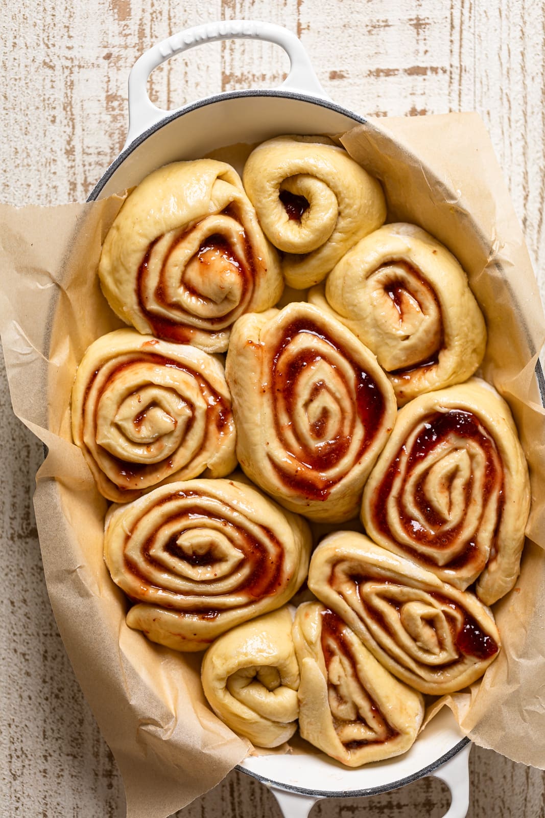 Uncooked Strawberry Sweet Rolls in a white, Le Creuset Dutch oven